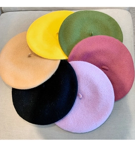 Flat lay of colorful wool berets in yellow, green, and red showing soft felt texture