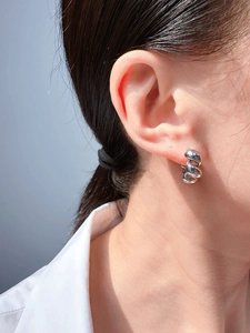 Detailed view of silver twisted hoop earring on a model showing modern minimalist style