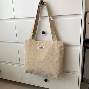 Detailed close-up of beige corduroy tote bag hanging on a minimalist handle