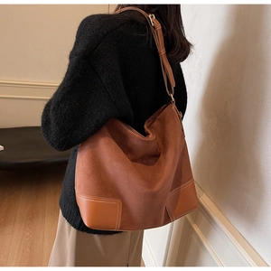 Detail of vintage brown suede tote bag showing stitching and side profile on shoulder
