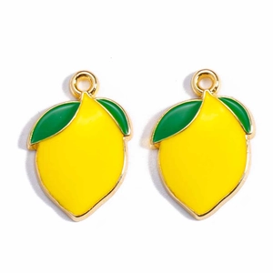 Detail view of two yellow lemon fruit pendants with green leaves for DIY jewelry