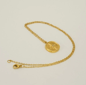 Detail of gold starburst medallion pendant with central crystal on a cable chain