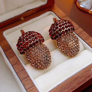 Macro shot of acorn earrings with red and champagne crystals in a wooden jewelry box