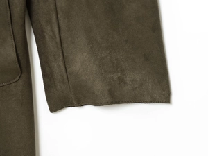 Detailed macro view of dark olive faux suede fabric texture and stitching on trench coat