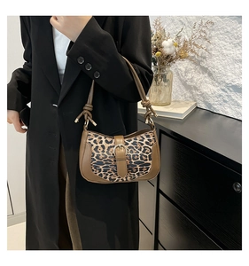 Detail of trendy leopard print shoulder bag worn with a dark coat in a lifestyle setting