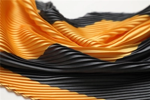 Macro shot of orange and black pleated scarf showing fine texture and silk feel
