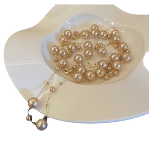 Collier élégant en perles de champagne avec chaîne dorée dans un plateau en céramique