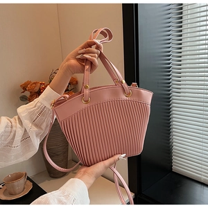 Detail of pink pleated leather handbag with golden metal rings and shoulder strap
