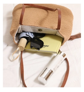 Flat lay of woven straw tote bag showing large capacity for sunglasses, books, and cosmetics