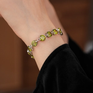 Macro view of court-style silver bracelet featuring round-cut green emerald zircons