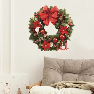 Couronne de Noël avec nœuds rouges, pommes de pin et poinsettia sur un mur blanc pur