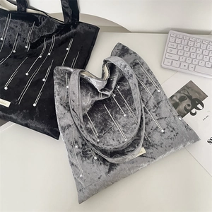 Detail of velvet tote bags with pearl embellishments beside a modern keyboard