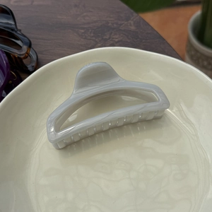 Detailed view of large 10cm marble textured claw clip in elegant cream ceramic plate
