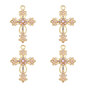 Detailed view of four gold cross charms inlaid with white pearls and sparkling zircons