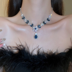 Close-up of zircon floral necklace with a blue teardrop pendant on model neck