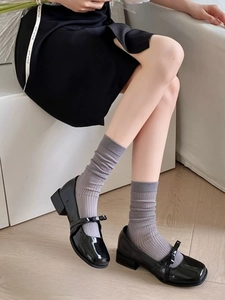 Close-up of grey ribbed calf socks worn with black patent leather Mary Jane shoes