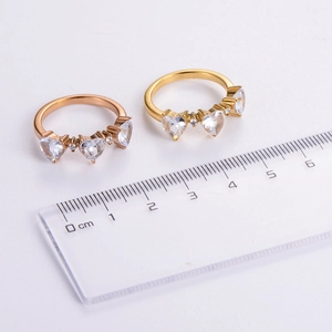 Detailed view of heart zircon rings in gold and rose gold with a measuring ruler