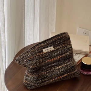 Detail of wool tweed cosmetic bag with Simple Wish label on a dark wood table
