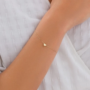 Close-up of elegant gold heart charm bracelet worn on a woman's wrist for daily style