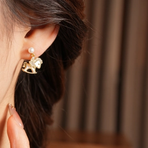 Detailed close-up of 14k gold plated horse earrings with pearls and crystals on a model