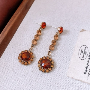 Détail macro de boucles d'oreilles vintage en bronze avec cristaux ambrés de style rétro