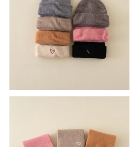Detail of knit baby hat and scarf set with white heart embroidery in multiple colors