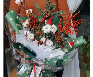 Christmas bouquet with cotton, pine cones, and red berries in snowflake wrapping paper