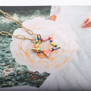 Detailed close-up of a gold star pendant featuring vibrant colorful enamel inlay on petals