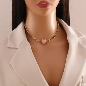 Elegant gold necklace with square pink cat eye stone displayed on a mannequin
