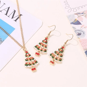 Detail of Christmas tree necklace and earrings set with red rhinestones and green enamel