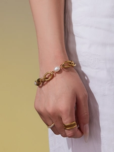 Detail of 18k gold plated chain bracelet with pearl and textured rings on model