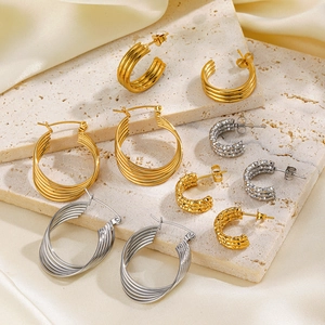 Chic gold and silver C-shaped hoop earrings displayed on a natural stone base