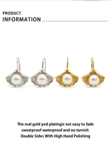 Detail of PVD gold plated shell earrings with white pearls and polished finish