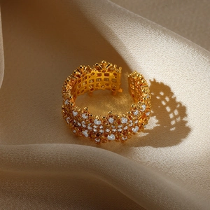 Detailed close-up of a golden hollow flower ring with small diamonds on beige silk