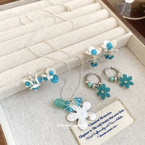Elegant silver flower jewelry set with pearls and turquoise stones on a jewelry tray