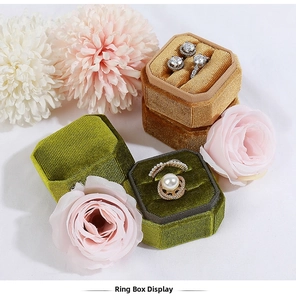 Top view of emerald and amber velvet octagonal jewelry boxes with rings and earrings