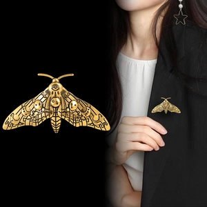 Vintage moth brooch in gold metal featuring celestial moon and eye patterns for suit lapels