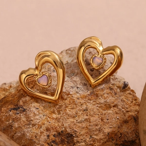 Detail of 18K gold hollow heart earrings with lavender opal stone on a stone background