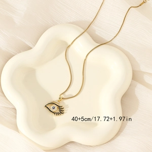 Golden heart devil eye pendant necklace with blue accents on cream ceramic plate