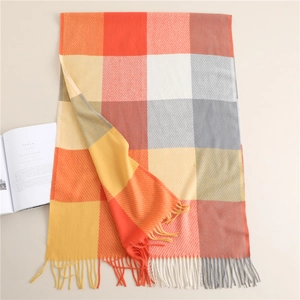 Detail of warm orange and grey plaid scarf with soft fringe tassels on a cozy background