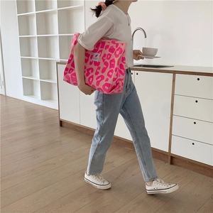 Lifestyle shot of a pink leopard print canvas tote bag carried in a modern home setting