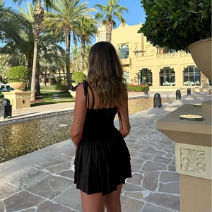 Vue de dos d'une robe d'été noire dos nu avec lacets et ourlet à volants superposés chic