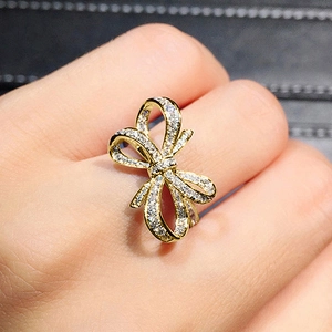 Vue macro d'une bague nœud dorée sertie de zircons cubiques portée au doigt