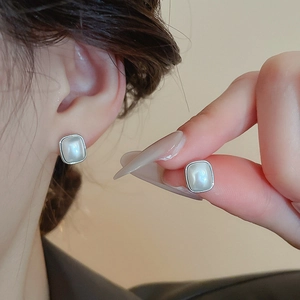 Gros plan de boucles d'oreilles carrées en argent avec pierre de lune portées à l'oreille