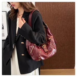 Detail of dark red hobo bag featuring vintage gold rivets and buckle on textured leather