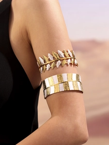 Dettaglio del set di bracciali da braccio dorati con foglie di alloro e smalto bianco