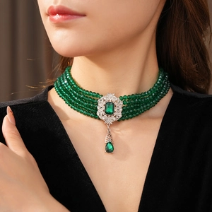 Macro detail of emerald green beaded choker with vintage royal drop pendant on model