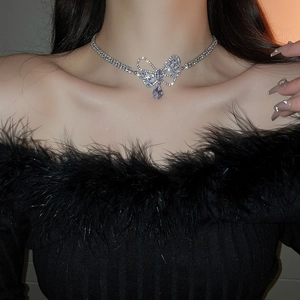 Close-up of silver bow necklace with zircon teardrop pendant worn by a model