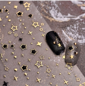 Detail of star-themed nail stickers with gold and black starry designs on manicure