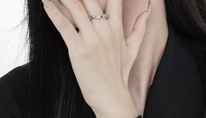Close-up of S925 silver irregular textured ring with green and white gemstones on finger